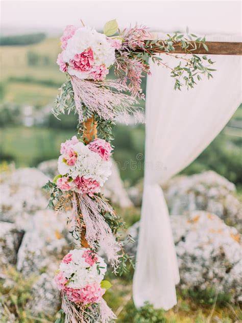 Arco nuziale in legno decorato con fiori e tessuti