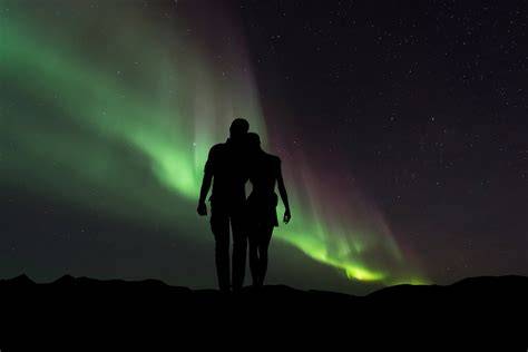 Coppia che ammira l'aurora boreale da una cabina con tetto in vetro