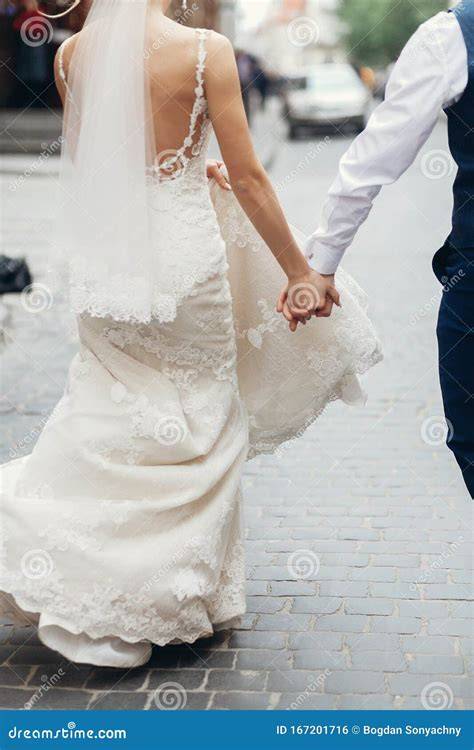 Coppia di sposi che si tiene per mano con sfondo floreale