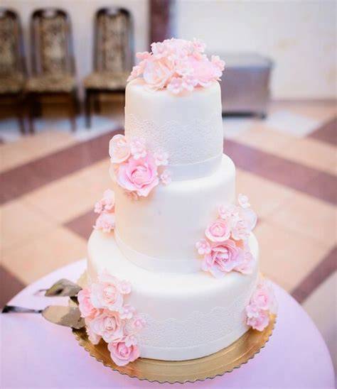 Torta nuziale bianca con fiori rosa e dettagli dorati
