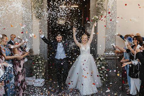 Coppia felice all'uscita dalla chiesa con auto da matrimonio
