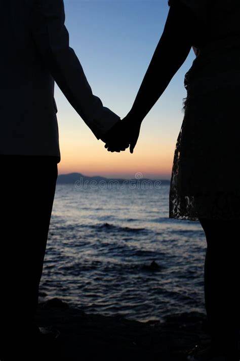 coppia che si tiene per mano durante un tramonto