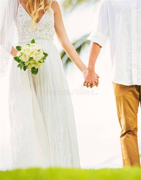 Coppia che si tiene per mano in abiti da sposa