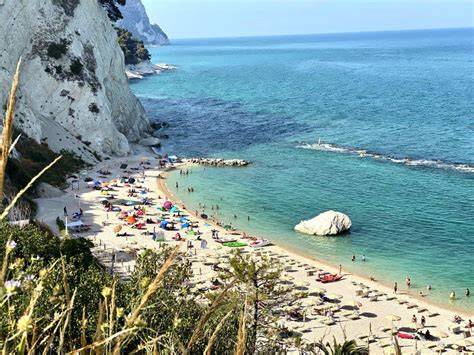 Imbarcazione a vela che naviga lungo la costa del Conero al tramonto