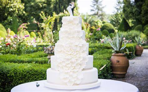 Torta nuziale bianca con fiori e foglie verdi