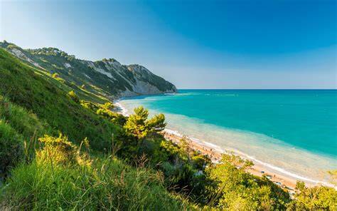 Imbarcazione che naviga al tramonto lungo la costa del Conero
