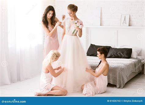 Gruppo di damigelle d'onore che aiutano la sposa a prepararsi