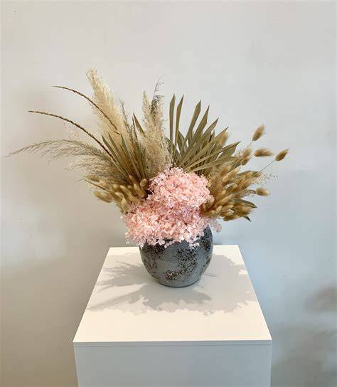 Composizione floreale con fiori stabilizzati e dettagli argentati