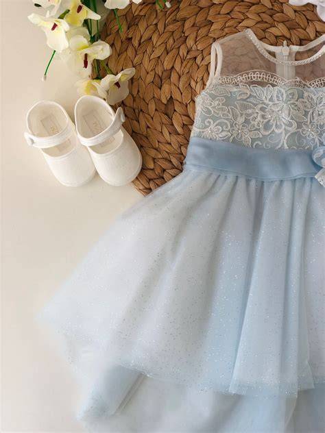 dettaglio cintura in tulle celeste e spilla floreale su abito da bambina