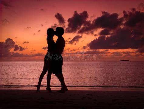 Coppia che si bacia sulla spiaggia al tramonto