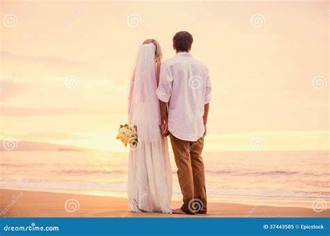 Coppia di sposi sulla spiaggia al tramonto